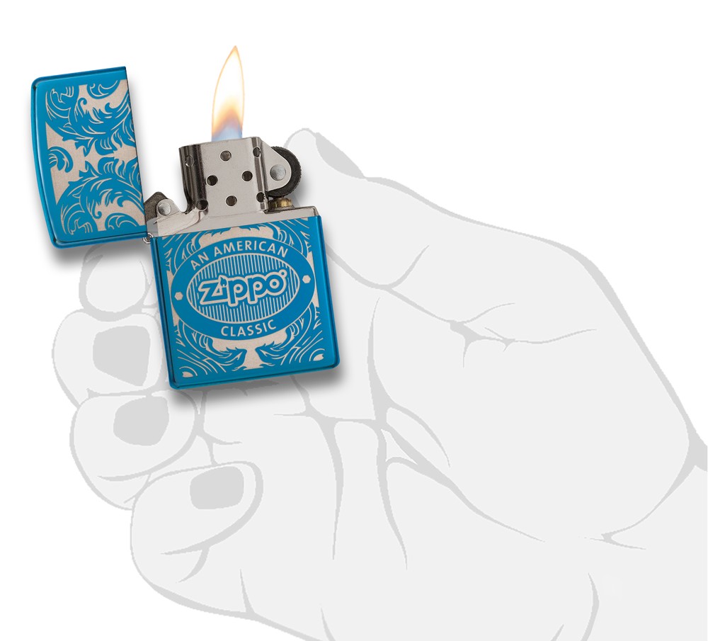 Blauwe Zippo-aansteker van voren gezien in een gestileerde open hand met vlam omgeven door een met laser gegraveerd filigraanmotief met het Zippo-logo en "an american classic".